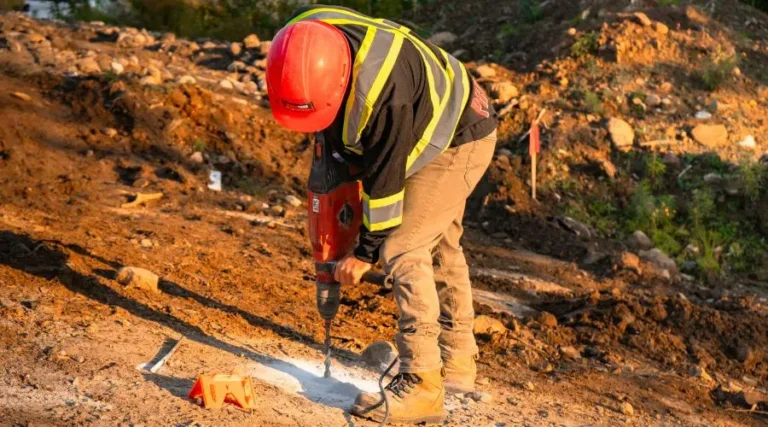 Man drilling holes to install screw piles for fences